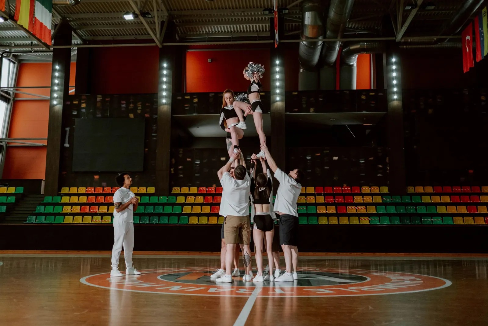 Une équipe de cheerleading réalise une pyramide avec une voltigeuse portée en hauteur dans un gymnase.