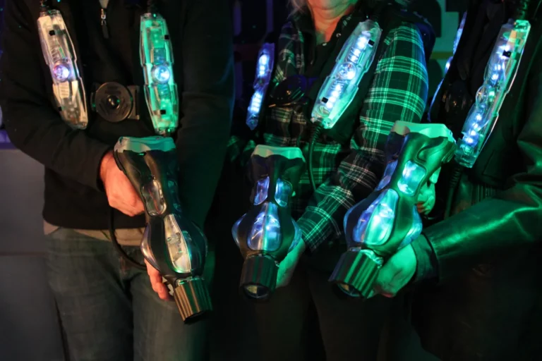 Joueurs de laser game tenant leurs pistolets, plastrons à capteurs allumés en vert