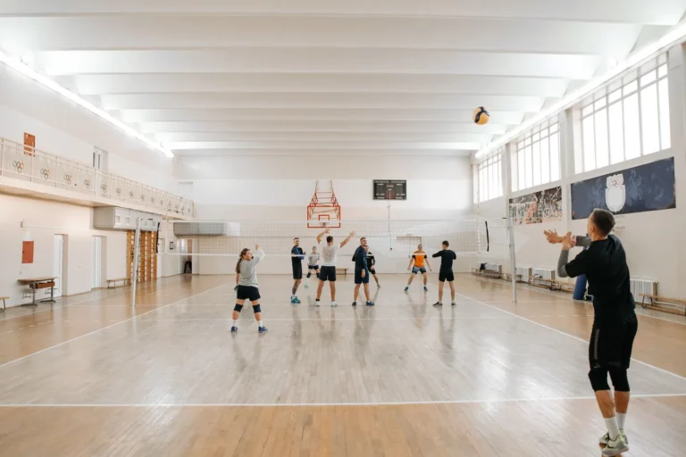 Gymnase municipal équipé, avec un groupe qui joue au volley-ball sous les paniers de basket